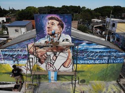 Seniman Marlene Zuriaga dan Lisandro Urteaga terlihat sedang menyelesaikan detail mural yang menggambarkan bintang sepak bola Argentina bernomor punggung 10 tersebut.  