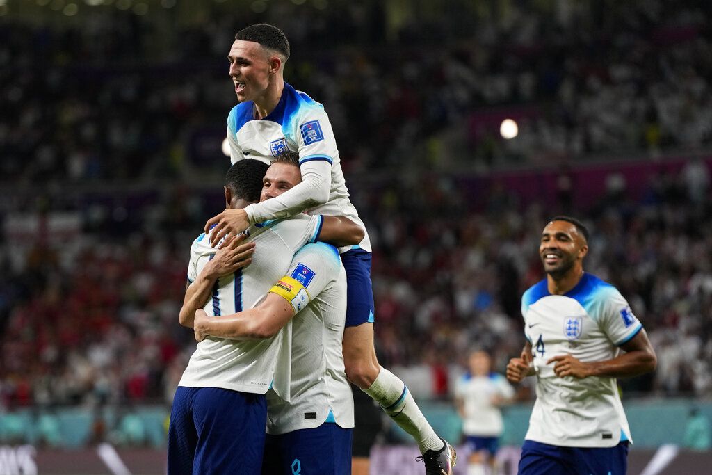 England's Marcus Rashford, left, celebrates with teammates after scoring his side's third goal during the World Cup group B soccer match between England and Wales, at the Ahmad Bin Ali Stadium in Al Rayyan , Qatar, Tuesday, Nov. 29, 2022. (AP Photo/Frank Augstein)