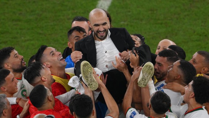 Morocco players throw Moroccos coach #00 Walid Regragui (C) in the air after they won the Qatar 2022 World Cup Group F football match between Canada and Morocco at the Al-Thumama Stadium in Doha on December 1, 2022, to advance to the round of 16. (Photo by Paul ELLIS / AFP) (Photo by PAUL ELLIS/AFP via Getty Images)