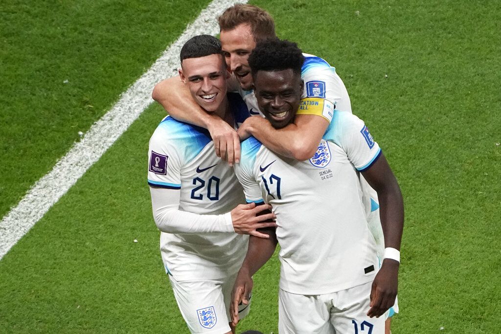 England's Bukayo Saka, right, celebrates with England's Phil Foden, left, and England's Harry Kane after scoring his side's 3rd goal during the World Cup round of 16 soccer match between England and Senegal, at the Al Bayt Stadium in Al Khor, Qatar, Sunday, Dec. 4, 2022. (AP Photo/Ariel Schalit)