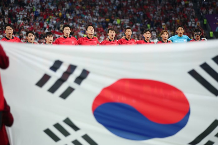 AL RAYYAN, QATAR - DECEMBER 02:  Korea Republic players lineup behind the national flag for the anthem prior to the FIFA World Cup Qatar 2022 Group H match between Korea Republic and Portugal at Education City Stadium on December 2, 2022 in Al Rayyan, Qatar. (Photo by Marc Atkins/Getty Images)