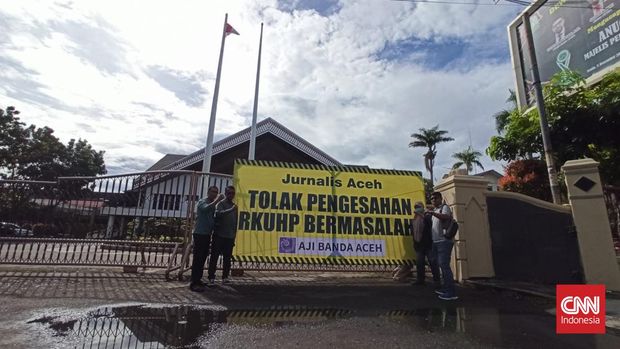 Aliansi Jurnalis Independen (AJI) membentangkan spanduk bertuliskan penolakan terhadap Revisi KUHP yang baru saja disahkan oleh DPR lewat rapat paripurna, Selasa (6/12/2022).