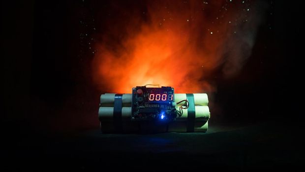 Image of a time bomb against dark background. Timer counting down to detonation illuminated in a shaft light shining through the darkness, conceptual image