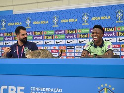 Kucing tersebut lantas menaiki meja yang ditempati Vinicius Junior dan staf media Timnas Brasil. (Foto: AFP via Getty Images/NELSON ALMEIDA)