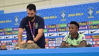 Kucing penyusup itu lantas diusir oleh staf media Brasil dari meja konferensi pers. Ada-ada saja, ya! (Foto: AFP via Getty Images/NELSON ALMEIDA)