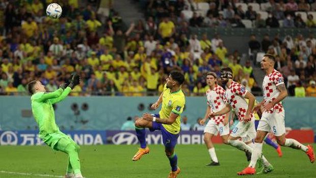 Croatia's goalkeeper #01 Dominik Livakovic saves a shot by Brazil's midfielder #07 Lucas Paqueta (2ndL) during the Qatar 2022 World Cup quarter-final football match between Croatia and Brazil at Education City Stadium in Al-Rayyan, west of Doha, on December 9, 2022. (Photo by ADRIAN DENNIS / AFP)