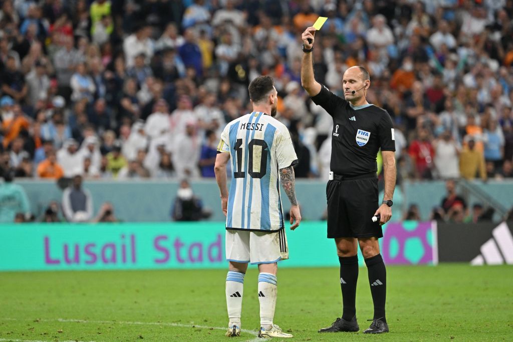 Spanish referee Antonio Mateu Lahoz shows a yellow card to Argentina's forward #10 Lionel Messi during the Qatar 2022 World Cup quarter-final football match between Netherlands and Argentina at Lusail Stadium, north of Doha, on December 9, 2022. (Photo by Alberto PIZZOLI / AFP) (Photo by ALBERTO PIZZOLI/AFP via Getty Images)