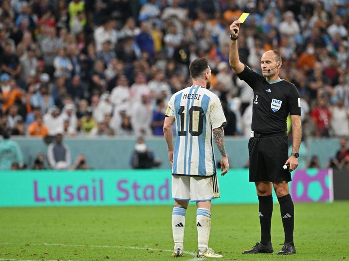 Spanish referee Antonio Mateu Lahoz shows a yellow card to Argentinas forward #10 Lionel Messi during the Qatar 2022 World Cup quarter-final football match between Netherlands and Argentina at Lusail Stadium, north of Doha, on December 9, 2022. (Photo by Alberto PIZZOLI / AFP) (Photo by ALBERTO PIZZOLI/AFP via Getty Images)