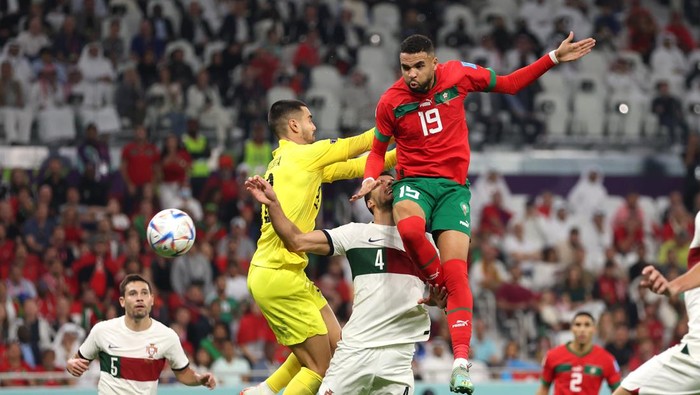 DOHA, QATAR - DECEMBER 10: Youssef En-Nesyri of Morocco rises above goalkeeper Diogo Costa and Ruben Dias of Portugal to head in the opening goal during the FIFA World Cup Qatar 2022 quarter final match between Morocco and Portugal at Al Thumama Stadium on December 10, 2022 in Doha, Qatar. (Photo by Francois Nel/Getty Images)