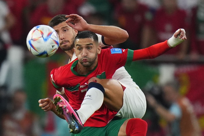 Moroccos Hakim Ziyech, foreground, fights for the ball with Portugals Ruben Dias during the World Cup quarterfinal soccer match between Morocco and Portugal, at Al Thumama Stadium in Doha, Qatar, Saturday, Dec. 10, 2022. (AP Photo/Petr David Josek)
