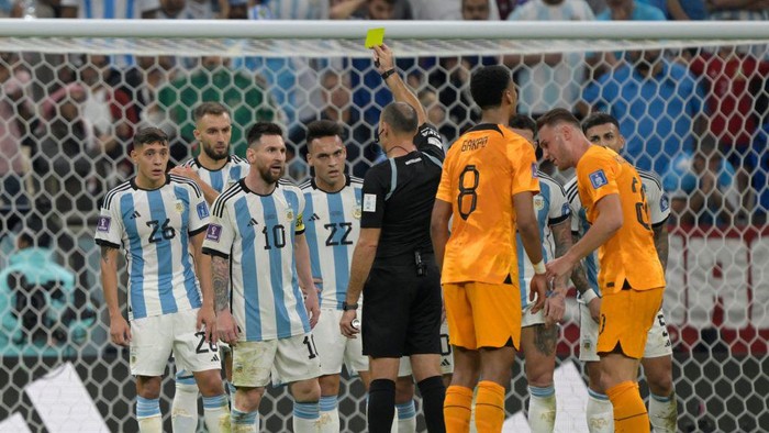 Spanish referee Antonio Mateu shows a yellow card to Argentinas forward #10 Lionel Messi during the Qatar 2022 World Cup quarter-final football match between The Netherlands and Argentina at Lusail Stadium, north of Doha on December 9, 2022. (Photo by JUAN MABROMATA / AFP) (Photo by JUAN MABROMATA/AFP via Getty Images)