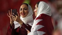 Dengan Piala Dunia di Qatar adalah momen bersejarah, fans tuan rumah pun tidak membuang kesempatan untuk terus mengabadikan setiap momennya. HP di tangan pun terus dimainkan. Foto: AFP via Getty Images/ADRIAN DENNIS