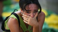 Brasil disingkirkan Kroasia di stadion Al Rayyan, Qatar. Di jalanan kota Rio De Janeiro, Brasil rasa kecewa ikut dirasakan seorang perempuan penggemar tim Samba. Ia sampai terduduk sambil larut dalam duka. Foto: AFP via Getty Images/CARL DE SOUZA  