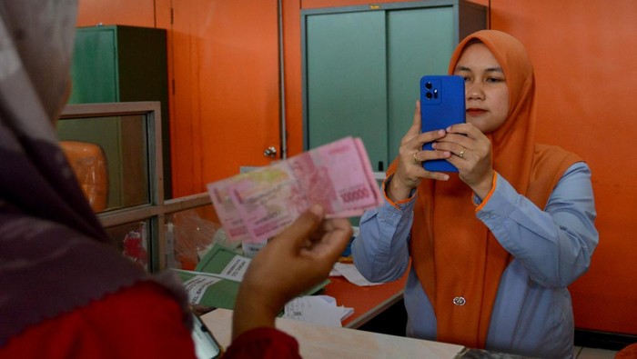 Petugas melayani warga mengambil pertolongan subsidi upah (BSU) di Kantor Pos Padang, Sumatera Barat, Senin (12/12/2022). PT Pos Indonesia mengingatkan bagi warga yang berhak memperoleh BSU untuk secepatnya mencairkan sebelum batas pengambilan pada 20 Desember 2022, alasannya yakni masih terdapat 1 juta pekerja menyanggupi syarat yang belum mengambil BSU.  ANTARA FOTO/Iggoy el Fitra/rwa.
