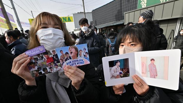 Fans hold pictures of BTS singer Jin in front of a military training unit in Yeoncheon on December 13, 2022, as the place where BTS singer Jin is scheduled to arrive to begin his military service. - BTS star Jin starts his mandatory South Korean military duty on December 13, 2022, the first band member to enlist since their hiatus announcement this year left fans heartbroken and wondering if this was the end for the K-pop juggernaut. (Photo by Jung Yeon-je / AFP)