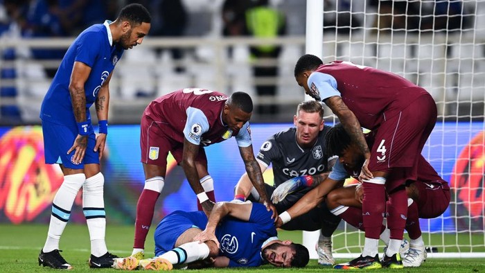 ABU DHABI, UNITED ARAB EMIRATES - DECEMBER 11: Armando Broja of Chelsea holds their leg, as teammates and players of Aston Villa offer support, during the Al Wahda Challenge Cup match between Chelsea and Aston Villa at Al Nahyan Stadium on December 11, 2022 in Abu Dhabi, United Arab Emirates. (Photo by Darren Walsh/Chelsea FC via Getty Images)