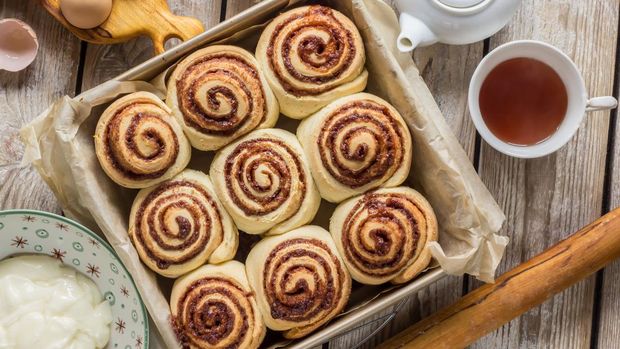 ilustrasi cinnamon roll Freshly baked cinnamon buns with spices and cocoa filling on parchment paper. Sweet Homemade Pastry christmas baking. Kanelbule - swedish dessert. Top view.
