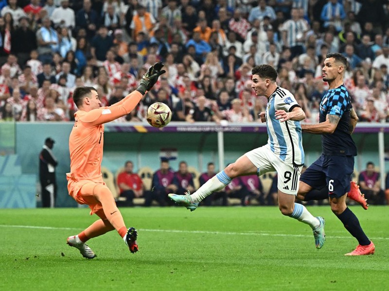 Argentina's forward #09 Julian Alvarez tries to score before being fouled by Croatia's goalkeeper #01 Dominik Livakovic (L) in the penalty box as Croatia's defender #06 Dejan Lovren looks on during the Qatar 2022 World Cup football semi-final match between Argentina and Croatia at Lusail Stadium in Lusail, north of Doha on December 13, 2022. (Photo by Jewel SAMAD / AFP) (Photo by JEWEL SAMAD/AFP via Getty Images)