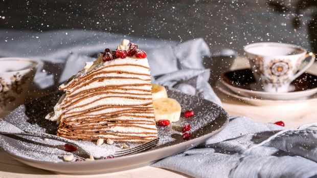 A slice of chocolate crepe cake on rustic background