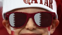 Seorang anak tampak gembira saat mengenakan atribut Qatar. (Zeki Fazlioglu/Getty Images)