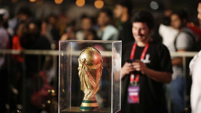 DOHA, QATAR - DECEMBER 15: People take a photo with the FIFA World Cup trophy exhibited in the Corniche Street of Doha, Qatar on December 15, 2022. (Photo by Ashraf Amra/Anadolu Agency via Getty Images)