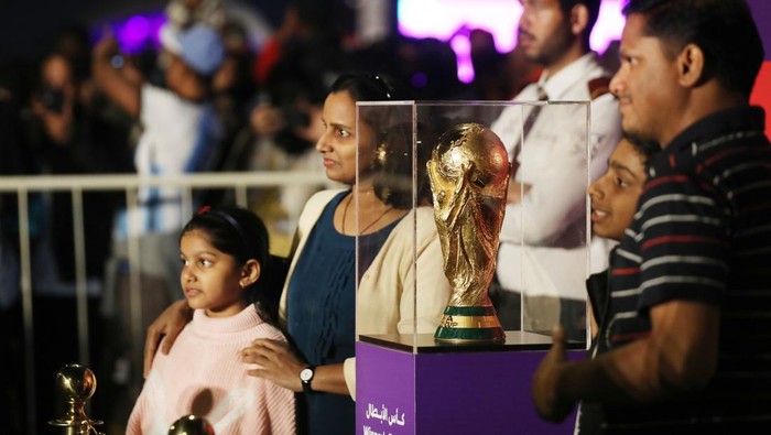 DOHA, QATAR - DECEMBER 15: People take a photo with the FIFA World Cup trophy exhibited in the Corniche Street of Doha, Qatar on December 15, 2022. (Photo by Ashraf Amra/Anadolu Agency via Getty Images)