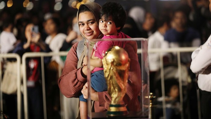 Warga Qatar Antre Panjang Demi Foto Bareng Trofi Piala Dunia 2022 DOHA, QATAR - DECEMBER 15: People take a photo with the FIFA World Cup trophy exhibited in the Corniche Street of Doha, Qatar on December 15, 2022. (Photo by Ashraf Amra/Anadolu Agency via Getty Images)