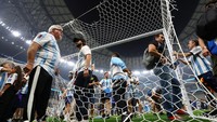 Penggemar Argentina memotong dan mengambil bagian dari jaring gawang selama perayaan di lapangan setelah pertandingan. Reuters/Kai Pfaffenbach  