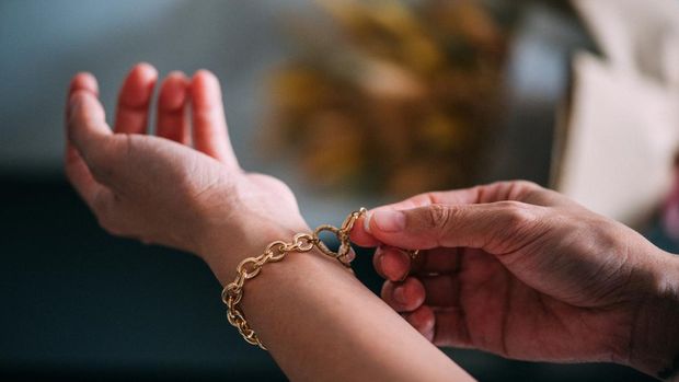 Close-up shot of women's choose gold bracelets on her hands. Entrepreneur's hand arranging the jewels to get the product ready and send it to her client .