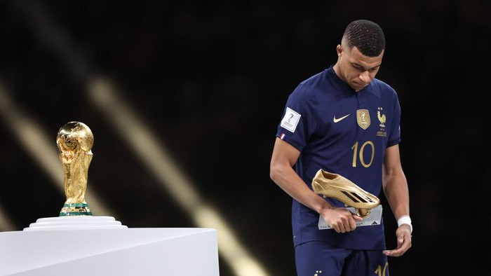 LUSAIL CITY, QATAR - DECEMBER 18: Kylian Mbappe of France walks past the FIFA World Cup Trophy after losing in the final with his golden boot trophy during the FIFA World Cup Qatar 2022 Final match between Argentina and France at Lusail Stadium on December 18, 2022 in Lusail City, Qatar. (Photo by Matthew Ashton - AMA/Getty Images)