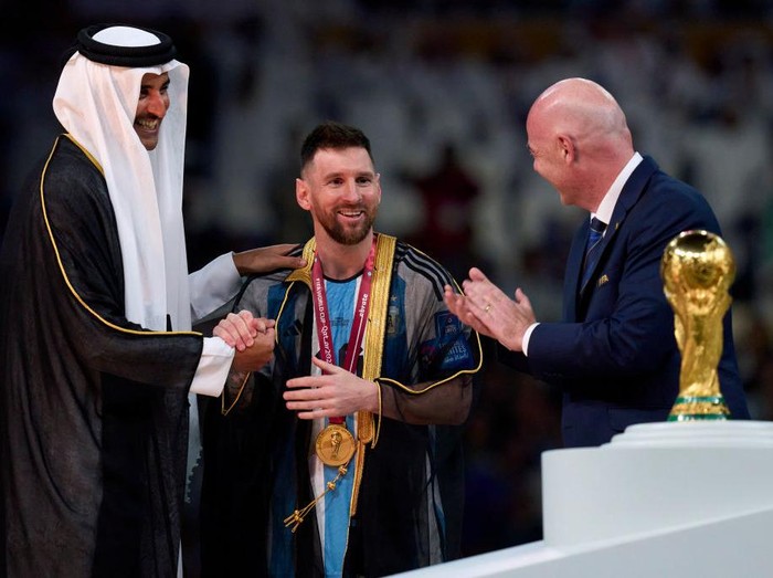 LUSAIL CITY, QATAR - DECEMBER 18: Lionel Messi of Argentina receives a Robe from Tamim bin Hamad Al Thani the Emir of Qatar  during the FIFA World Cup Qatar 2022 Final match between Argentina and France at Lusail Stadium on December 18, 2022 in Lusail City, Qatar. (Photo by Quality Sport Images/Getty Images)