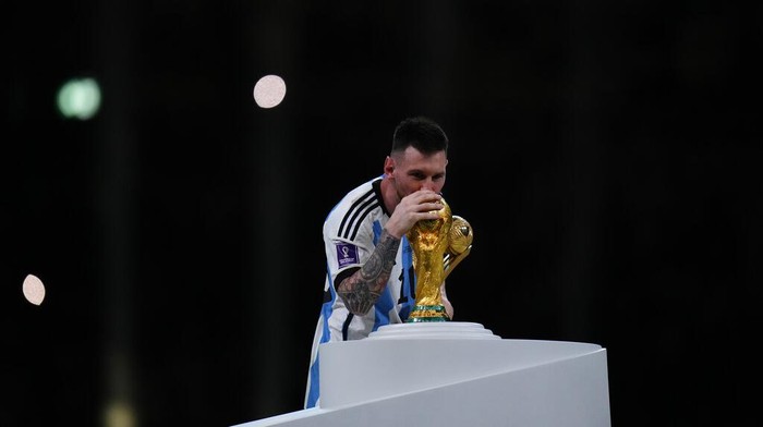 Argentinas Lionel Messi holds best player of the tournament trophy as he kisses the World Cup trophy after the World Cup final soccer match between Argentina and France at the Lusail Stadium in Lusail, Qatar, Sunday, Dec. 18, 2022. (AP Photo/Petr David Josek)