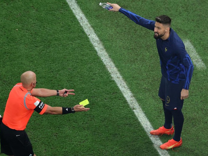 Polish referee Szymon Marciniak shows a yellow card to France's forward #09 Olivier Giroud while on the bench during the Qatar 2022 World Cup football final match between Argentina and France at Lusail Stadium in Lusail, north of Doha on December 18, 2022. (Photo by Giuseppe CACACE / AFP) (Photo by GIUSEPPE CACACE/AFP via Getty Images)