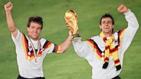 Gelandang Jerman Barat Lothar Matthaeus (kiri) dan penyerang Pierre Littbarski merayakan dengan trofi Piala Dunia setelah timnya mengalahkan juara bertahan Argentina 1-0 melalui tendangan penalti di final Piala Dunia 1990, di Roma, Italia, Minggu (8/7/1990). (AFP/Getty Images)  