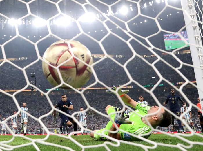 LUSAIL CITY, QATAR - DECEMBER 18: (EDITORS NOTE: In this photo taken from a remote camera from behind the goal) Kylian Mbappe of France scores the team's first goal from the penalty spot past Emiliano Martinez of Argentina during the FIFA World Cup Qatar 2022 Final match between Argentina and France at Lusail Stadium on December 18, 2022 in Lusail City, Qatar. (Photo by Catherine Ivill/Getty Images)