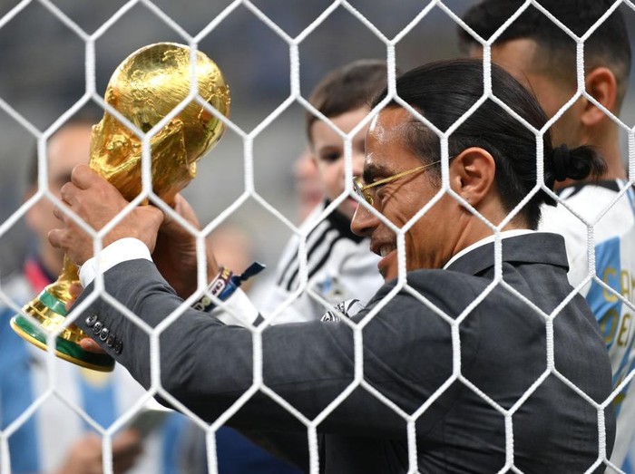 LUSAIL CITY, QATAR - DECEMBER 18: Nusret Goekce, nicknamed Salt Bae, admires the FIFA World Cup Qatar 2022 Winner's Trophy after the FIFA World Cup Qatar 2022 Final match between Argentina and France at Lusail Stadium on December 18, 2022 in Lusail City, Qatar. (Photo by Dan Mullan/Getty Images)