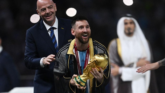 Soccer Football - FIFA World Cup Qatar 2022 - Final - Argentina v France - Lusail Stadium, Lusail, Qatar - December 18, 2022   Argentina's Lionel Messi receives the trophy from the FIFA president Gianni Infantino during the trophy presentation REUTERS/Dylan Martinez