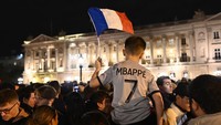 Rakyat Prancis menyalakan suar dan mengibarkan bendera Prancis di depan Hotel de Crillon (Foto: Anadolu Agency via Getty Images/Anadolu Agency)