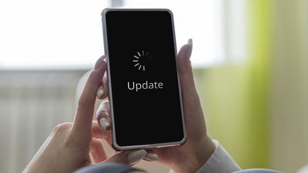 online update of the operating system or applications on the smartphone screen. A young woman is holding a smartphone in her hands.