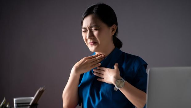 Asian woman in blue shirt was sick with fever, working on a laptop at office. isolated on white background. Low key.