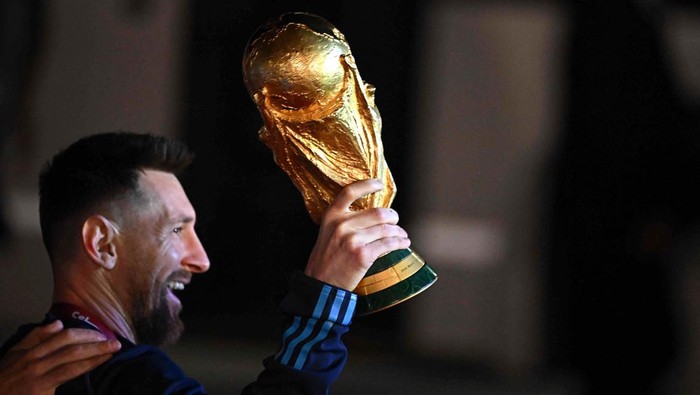 Argentinas captain and forward Lionel Messi holds the FIFA World Cup Trophy upon arrival at Ezeiza International Airport after winning the Qatar 2022 World Cup tournament in Ezeiza, Buenos Aires province, Argentina on December 20, 2022. (Photo by Luis ROBAYO / AFP) (Photo by LUIS ROBAYO/AFP via Getty Images)