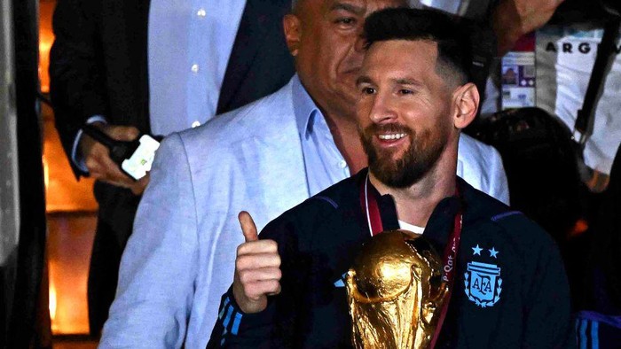 Argentinas captain and forward Lionel Messi (C) holds the FIFA World Cup Trophy alongside Argentinas coach Lionel Scaloni (R) upon arrival at Ezeiza International Airport after winning the Qatar 2022 World Cup tournament in Ezeiza, Buenos Aires province, Argentina on December 20, 2022. (Photo by Luis ROBAYO / AFP) (Photo by LUIS ROBAYO/AFP via Getty Images)