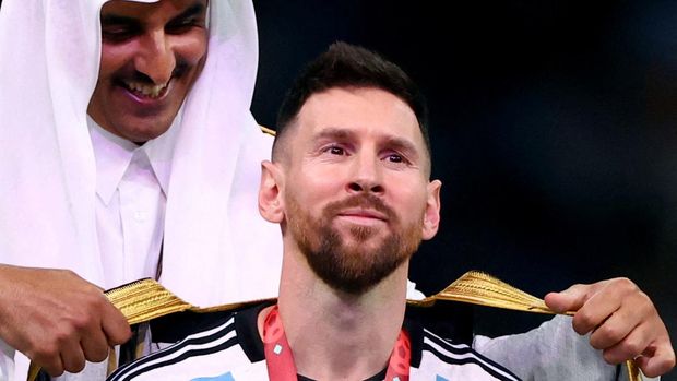 Soccer Football - FIFA World Cup Qatar 2022 - Final - Argentina v France - Lusail Stadium, Lusail, Qatar - December 18, 2022   A robe is put on Argentina's Lionel Messi by Emir of Qatar Sheikh Tamim bin Hamad Al Thani during the trophy ceremony REUTERS/Hannah Mckay     TPX IMAGES OF THE DAY