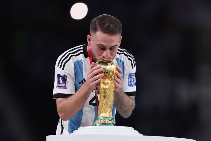 LUSAIL CITY, QATAR - DECEMBER 18: Alexis Mac Allister of Argentina kisses the FIFA World Cup Qatar 2022 Winners Trophy during the FIFA World Cup Qatar 2022 Final match between Argentina and France at Lusail Stadium on December 18, 2022 in Lusail City, Qatar. (Photo by Clive Brunskill/Getty Images)