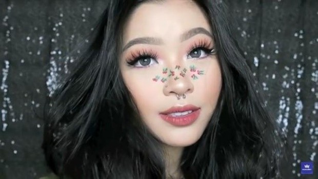 Cindercella mengaplikasikan tampilan makeup look Natal dengan menghias tanaman misleteo di bagian antara hidung dan pipi