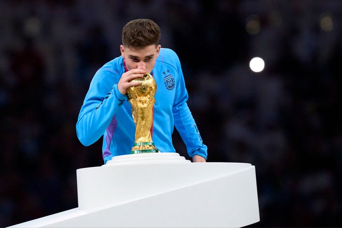 LUSAIL CITY, QATAR - DECEMBER 18: Julian Alvarez of Argentina kisses the FIFA World Cup Winners Trophy at the award ceremony following the FIFA World Cup Qatar 2022 Final match between Argentina and France at Lusail Stadium on December 18, 2022 in Lusail City, Qatar. (Photo by Juan Luis Diaz/Quality Sport Images/Getty Images)