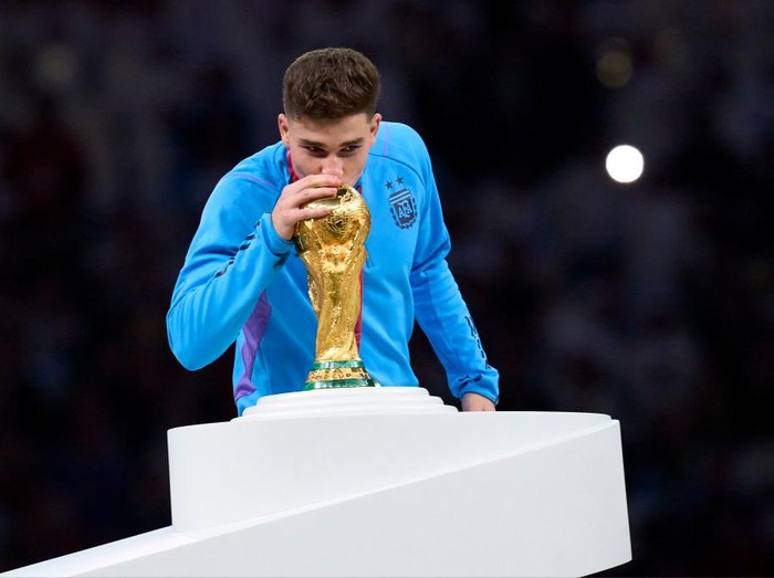 LUSAIL CITY, QATAR - DECEMBER 18: Julian Alvarez of Argentina kisses the FIFA World Cup Winner's Trophy at the award ceremony following the FIFA World Cup Qatar 2022 Final match between Argentina and France at Lusail Stadium on December 18, 2022 in Lusail City, Qatar. (Photo by Juan Luis Diaz/Quality Sport Images/Getty Images)