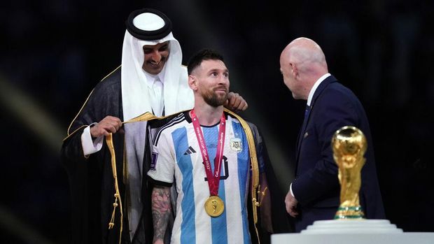 Emir of Qatar, Sheikh Tamim bin Hamad Al Thani dresses Argentina's Lionel Messi with traditional Arab bisht ahead of the Trophy presentation as FIFA President Gianni Infantino looks on following the FIFA World Cup final at Lusail Stadium, Qatar. Picture date: Sunday December 18, 2022. (Photo by Mike Egerton/PA Images via Getty Images)