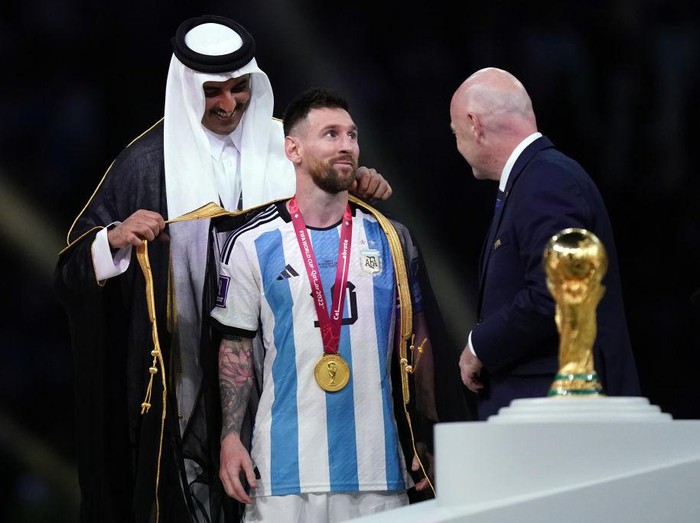 Emir of Qatar, Sheikh Tamim bin Hamad Al Thani dresses Argentina's Lionel Messi with traditional Arab bisht ahead of the Trophy presentation as FIFA President Gianni Infantino looks on following the FIFA World Cup final at Lusail Stadium, Qatar. Picture date: Sunday December 18, 2022. (Photo by Mike Egerton/PA Images via Getty Images)
