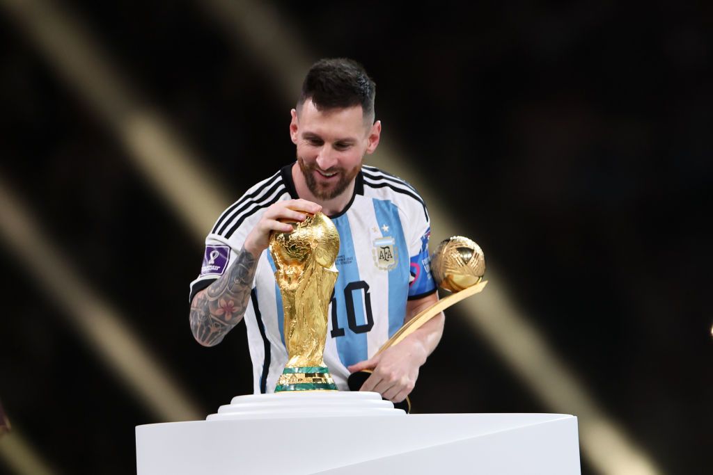 LUSAIL CITY, QATAR - DECEMBER 18: Lionel Messi of Argentina admires the FIFA World Cup Trophy at the awards ceremony during the FIFA World Cup Qatar 2022 Final match between Argentina and France at Lusail Stadium on December 18, 2022 in Lusail City, Qatar. (Photo by Matthew Ashton - AMA/Getty Images)